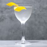 Wet Martini in Nick & Nora glass with paisley etching garnished with a lemon twist, on a dark marble background