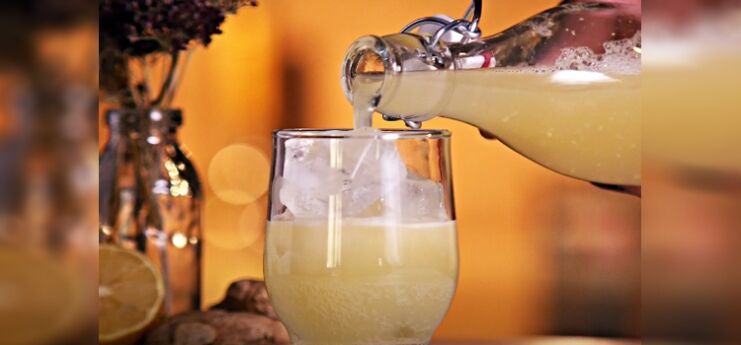 pouring bottle of ginger beer on a glass with ice